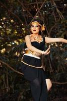 Balinese woman dancing on the top of the rock while wearing a black costume and a golden crown on her head photo