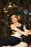 Javanese woman with golden crown and black costume chilling inside the forest while wearing makeup photo