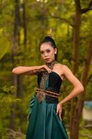 A brave Asian woman in makeup wearing a green costume and gold jewelry with the woods in the background photo