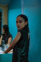 A portrait of a wet girl standing in front of the mirror and the blue wall with smile faces photo