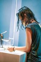 A Young Woman washes her hands in the white sink from the virus Covid-19 photo