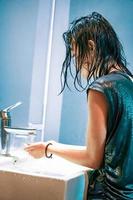 una joven se lava las manos en el lavabo blanco del virus covid-19 foto