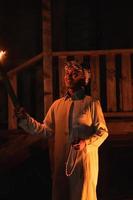 An Arabian man holding a fire torch in the front of a wooden house photo