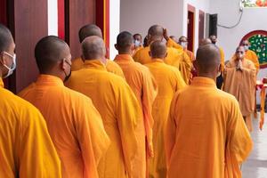 Bandung City, Indonesia, 2022 - A Group of monks with orange and red robes praying together at the altar photo