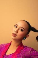 Javanese woman with black hair wearing makeup and a pink dress called kebaya photo