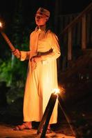 A Muslim man standing with the fire torch in her hand at the front of the village photo