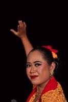 Close-up face of a Balinese woman during the traditional dance performance while wearing an orange costume and makeup photo