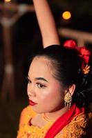 The beautiful closeup face of a Javanese woman with make-up at a traditional dance performance while wearing a yellow costume photo