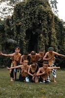 A Group of Indonesian people dancing pose in a golden suit while wearing makeup on the green grass photo