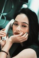 Asian women make a phone call while wearing a black dress and bracelet in her hand photo