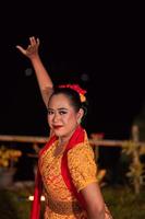 Close-up face of a Balinese woman during the traditional dance performance while wearing an orange costume and makeup photo