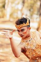 Javanese mane dancing in shirtless while wearing a golden crown and golden accessories photo