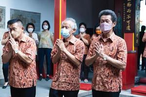 Bandung City, Indonesia, 2022 - The congregation and the monks standing together while praying at the altar to respect the god photo