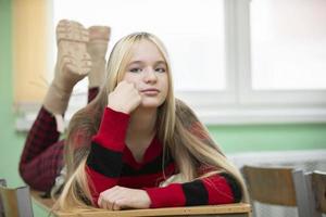 una adolescente yace en un pupitre escolar. estudiante de preparatoria. niña de quince años. foto