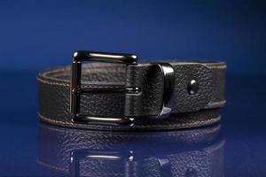 Black leather belt on a dark blue background. photo