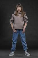 Beautiful fashion model girl of ten years in full growth on a gray background. photo