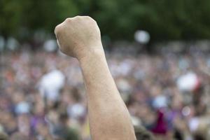 una mano en un puño en protesta contra una multitud borrosa de personas. foto