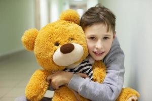 A little boy hugs a fluffy teddy bear. photo