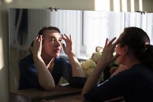 Woman looking at wrinkles in the mirror. photo