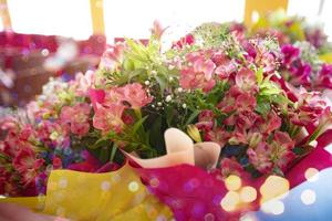 Pink flowers in bouquets on a light background.Pink lily flowers around green leaves. Close up beautiful colorful flower bouquet with lily. photo