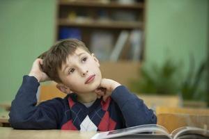 Elementary school boy in a classroom with a book. Child at school. photo