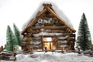 casa de madera en miniatura y árboles de navidad en la nieve. foto