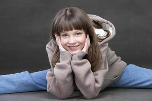 A beautiful middle school age girl in jeans looks at the camera and smiles. Nine-year-old girl of beautiful appearance. photo