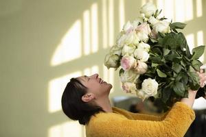 Happy middle-aged woman with a huge bouquet of roses rejoices.Woman fifty years old. photo