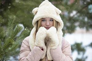 hermosa chica en un sombrero de piel y mitones sobre un fondo de invierno. foto