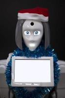 Robot with a blank information display in a Christmas hat close-up on a black background. photo