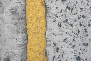 Old road background with yellow lines peeling off from aging. photo