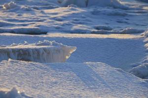 ice hummocks are covered with snow, illuminated by the rays of the winter sun photo