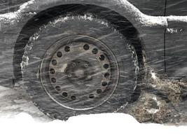 winter road, the car makes its way through a snowstorm, the wheel in a snowdrift photo