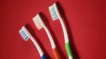 3 different colored toothbrushes isolated on a red background photo