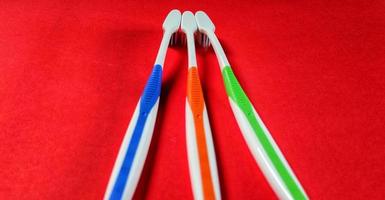 Three different colored toothbrushes isolated on red background photo