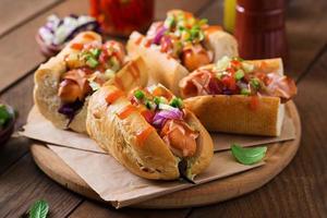 Hot dog - sandwich with Mexican salsa on wooden background. photo