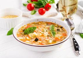 Minestrone, italian vegetable soup with pasta on white table. Vegan soup. photo