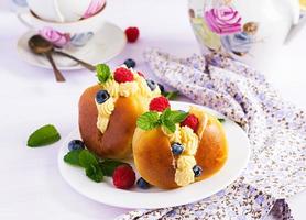 Rum baba decorated with whipped cream and fresh raspberry, blueberry. Savarin with rum, cream and berries. Italian cuisine photo