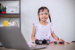 Asian students learn at home by coding robot cars and electronic board cables in STEM, STEAM, mathematics engineering science technology computer code in robotics for kids' concepts. photo