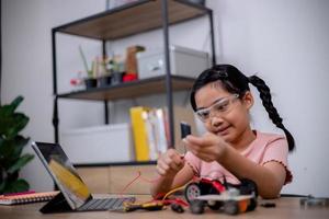 Asian students learn at home by coding robot cars and electronic board cables in STEM, STEAM, mathematics engineering science technology computer code in robotics for kids' concepts. photo