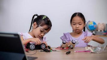 los estudiantes asiáticos aprenden en casa codificando automóviles robot y cables de placas electrónicas en tallo, vapor, ingeniería matemática, ciencia, tecnología, código informático en robótica para conceptos infantiles. foto