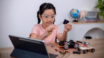 Asian students learn at home by coding robot cars and electronic board cables in STEM, STEAM, mathematics engineering science technology computer code in robotics for kids' concepts. photo