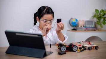 Asian students learn at home by coding robot cars and electronic board cables in STEM, STEAM, mathematics engineering science technology computer code in robotics for kids' concepts. photo