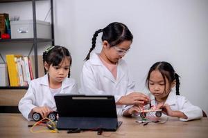 los estudiantes asiáticos aprenden en casa codificando automóviles robot y cables de placas electrónicas en tallo, vapor, ingeniería matemática, ciencia, tecnología, código informático en robótica para conceptos infantiles. foto