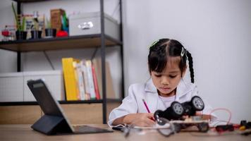 Asian students learn at home by coding robot cars and electronic board cables in STEM, STEAM, mathematics engineering science technology computer code in robotics for kids' concepts. photo