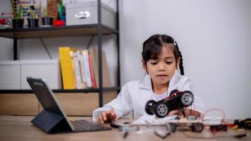 Asian students learn at home by coding robot cars and electronic board cables in STEM, STEAM, mathematics engineering science technology computer code in robotics for kids' concepts. photo