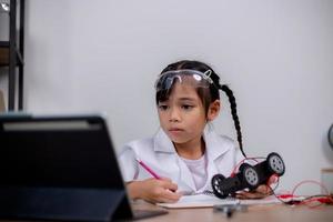 los estudiantes asiáticos aprenden en casa codificando automóviles robot y cables de placas electrónicas en tallo, vapor, ingeniería matemática, ciencia, tecnología, código informático en robótica para conceptos infantiles. foto