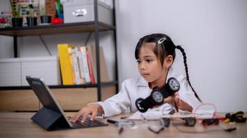 Asian students learn at home by coding robot cars and electronic board cables in STEM, STEAM, mathematics engineering science technology computer code in robotics for kids' concepts. photo