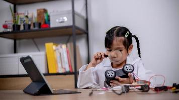 Asian students learn at home by coding robot cars and electronic board cables in STEM, STEAM, mathematics engineering science technology computer code in robotics for kids' concepts. photo