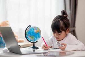 Asian little girl is learning the globe model, concept of save the world and learn through play activity for kid education at home. photo